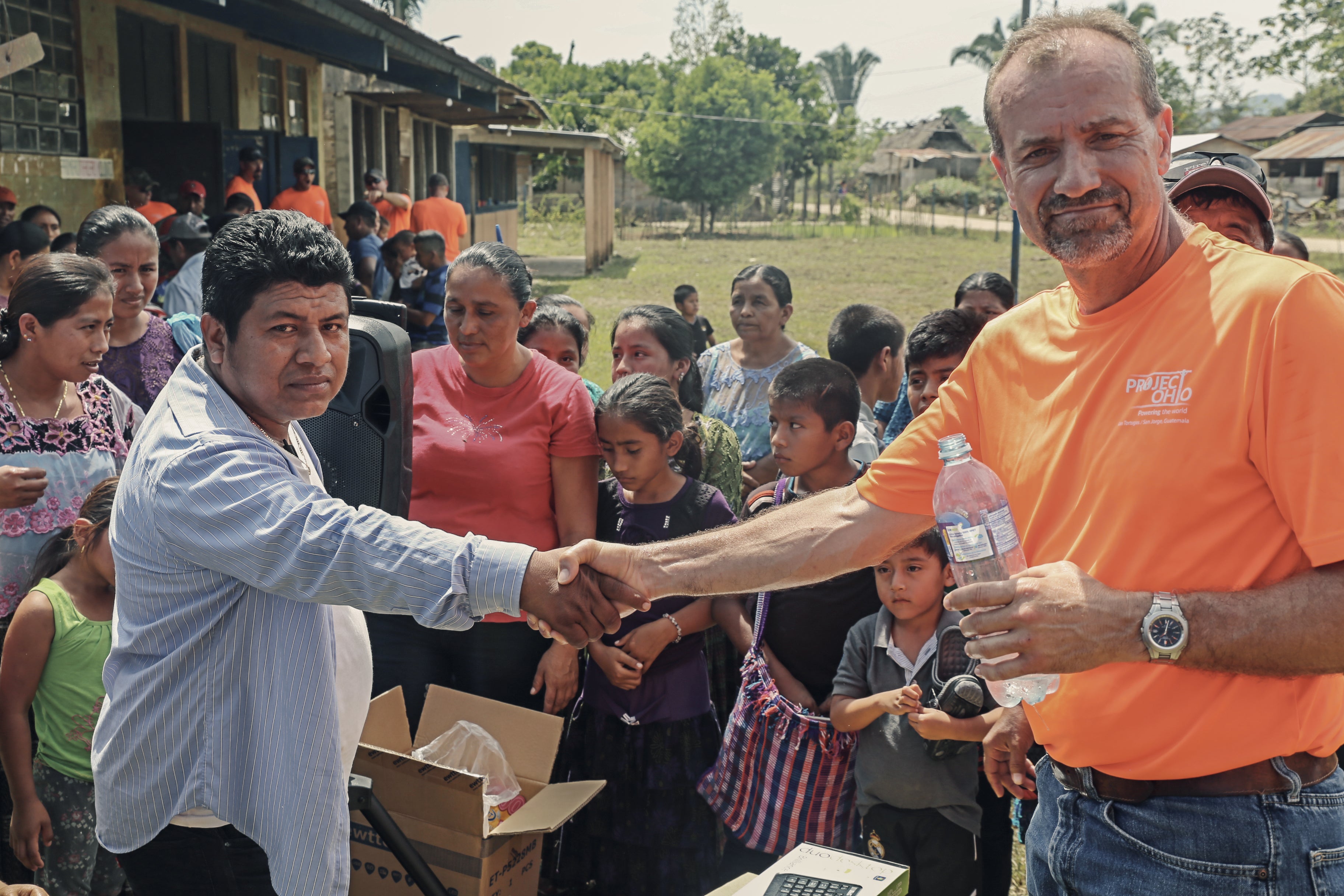 Two people shaking hands in front of a group of others