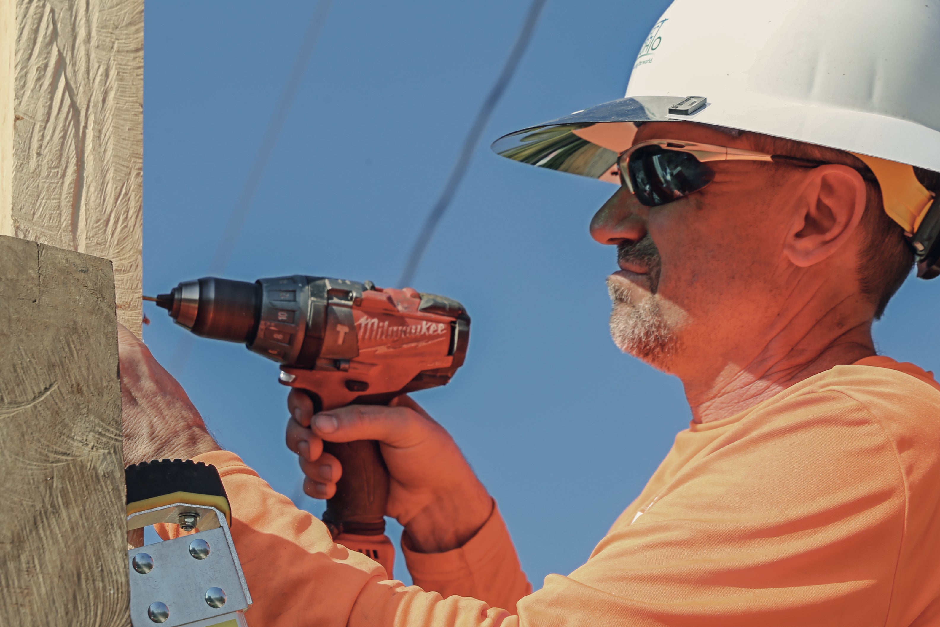 A man using a drill on a utility pole