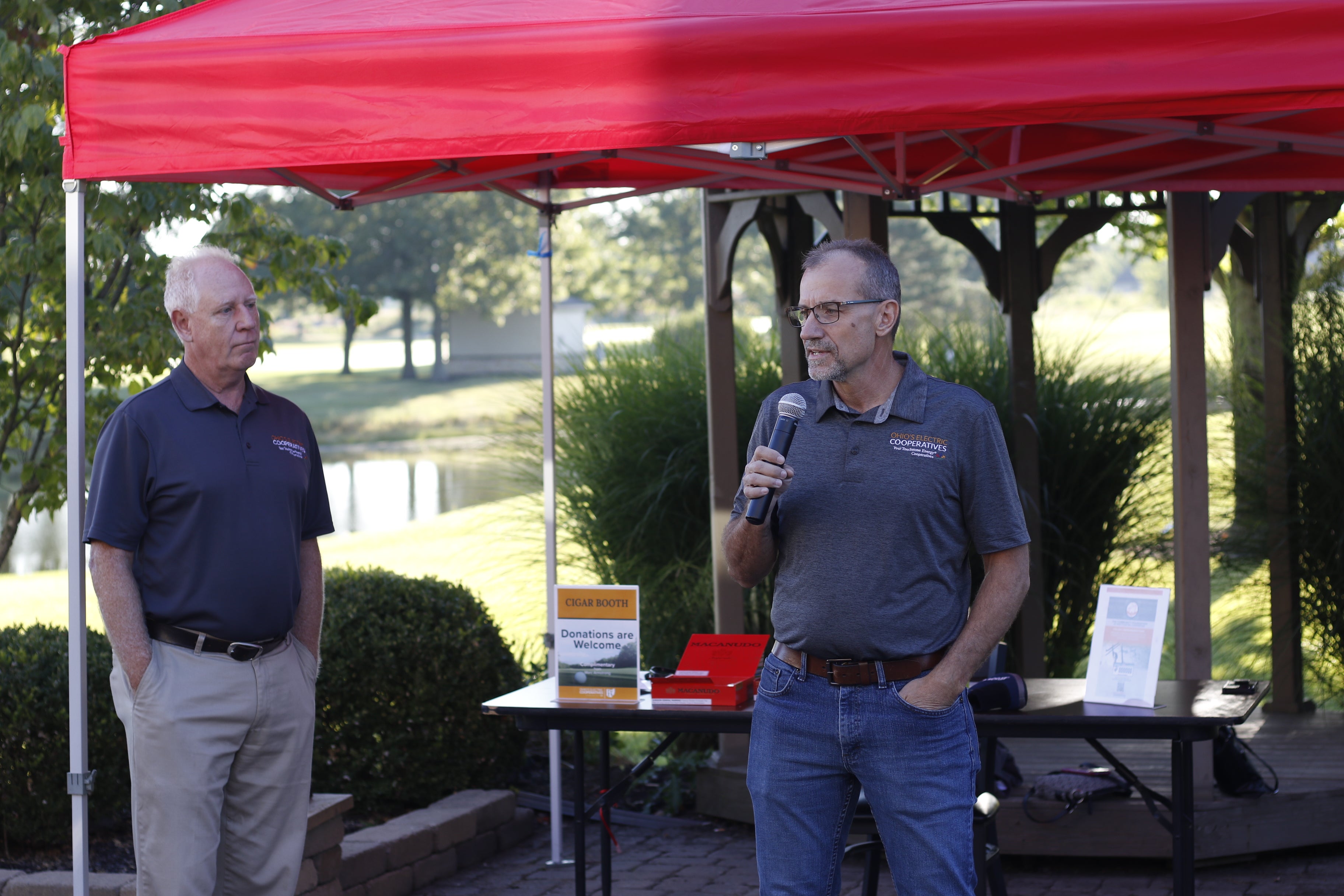 A man speaking into a microphone in front of a tent