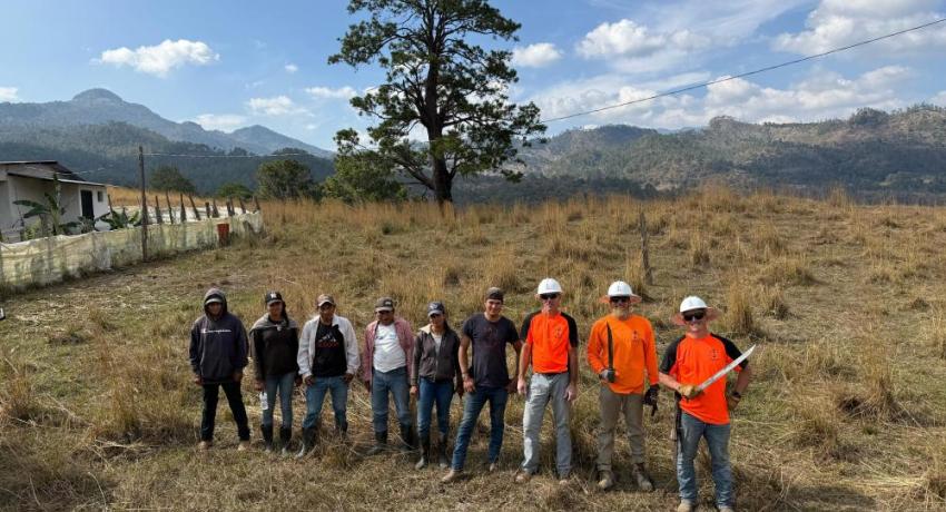 A group of lineworkers posing in a field in Guatemala